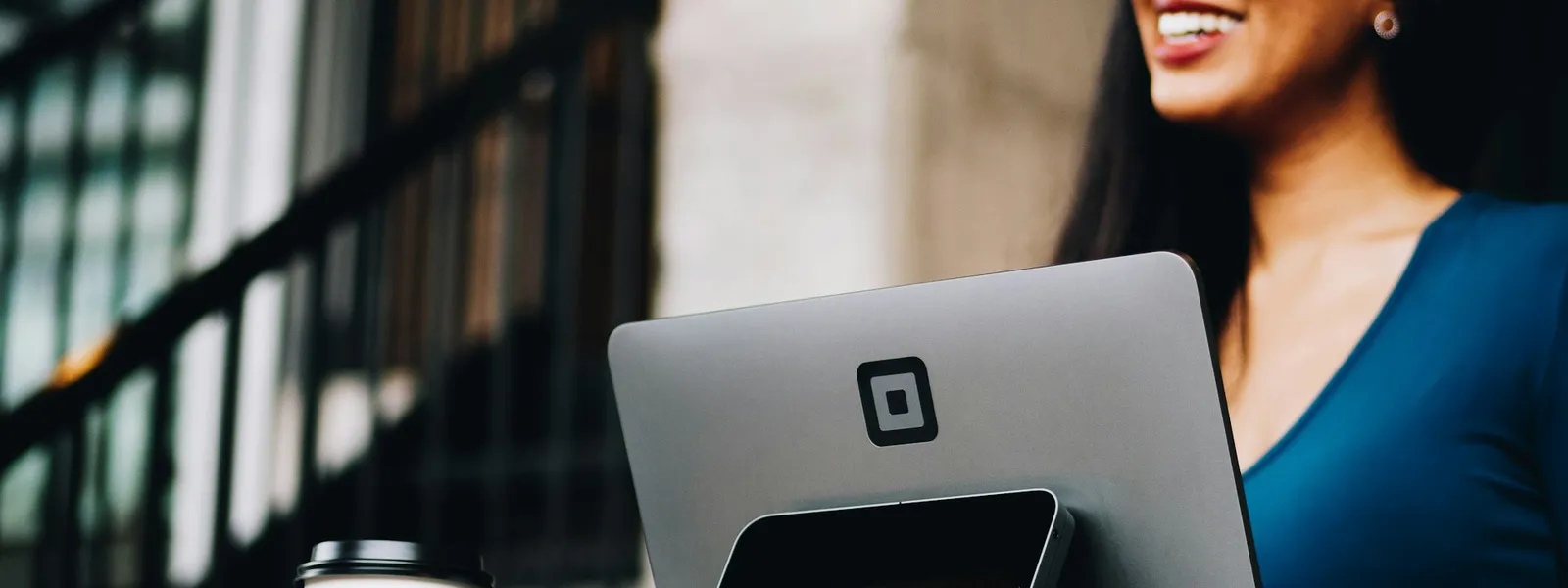 Atendente de loja sorrindo enquanto faz a cobrança de um cliente com um cartão de crédito